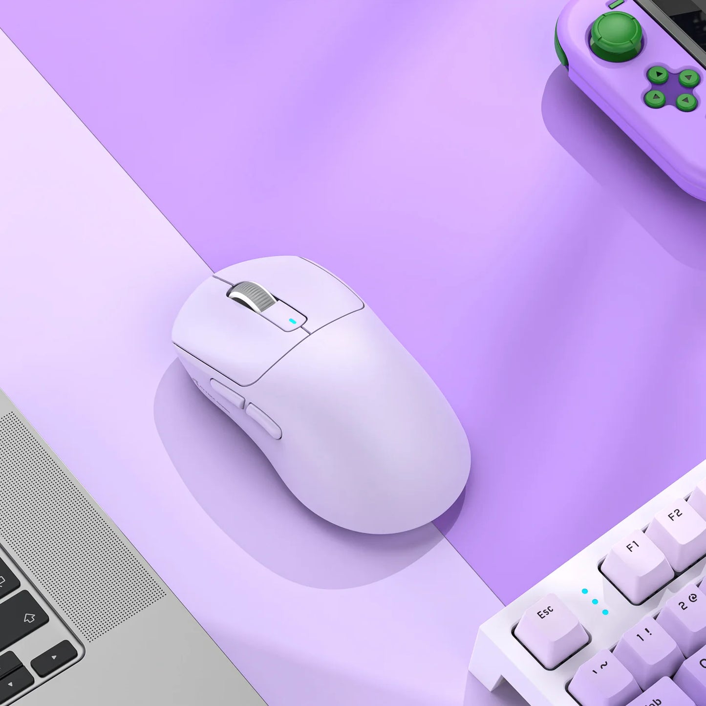 White computer mouse on a purple surface with a keyboard and gaming controller in the background